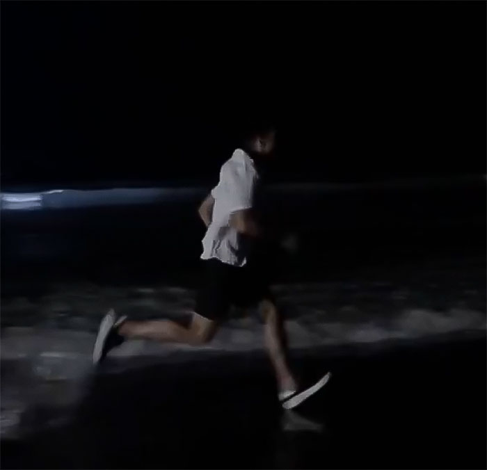 Man running on a dark beach at night, linked to messy reality show event.