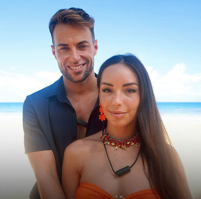 Man and woman at the beach, capturing a moment on a reality show.