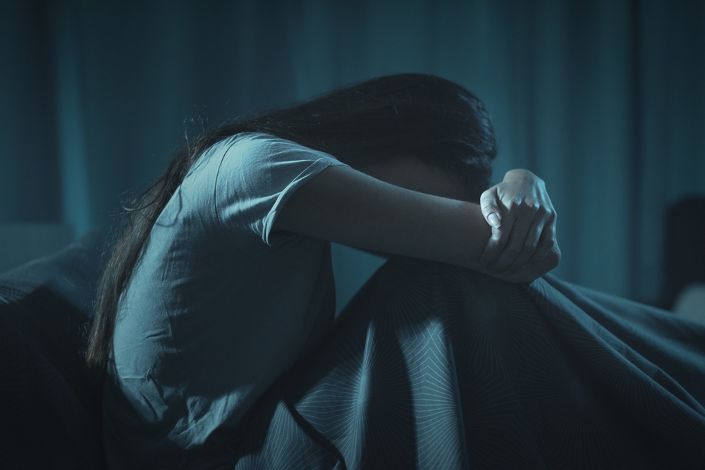 Depressed woman sitting in her bed at night, she can't sleep
